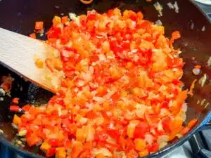 Het nationale gerecht: riz gras Waarschuwing. Het nationale gerecht van Burkina Faso heet ‘riz gras’. Dat klinkt nog wel leuk in het Frans, maar de letterlijke vertaling van dit gerecht is ‘vette rijst’. Hm, dat klinkt minder. De reden dat dit gerecht zo heet is dat de Burkinabé er onmogelijk veel van hun pinda-olie in gooien. Dat leek me toch niet zo fijn, dus heb ik het gerecht op dat punt wat aangepast naar wat wij gezonder of fijner vinden; veel minder olie dus. En je mag van mij pinda-olie gebruiken, zoals de Burkinabé doen, maar als je er andere olie voor wilt gebruiken, vind ik het ook oké. Verder is het een makkelijk basisgerecht dat je eventueel naar eigen smaak kunt aanpassen. Ik heb er bijvoorbeeld kip bij gedaan. Dat kan, maar ‘riz gras’ is vooral het basisrecept voor rijst met tomaten en eventueel andere groenten. De basisbereiding is simpel: Mix de tomaat, paprika en chilipeper door elkaar (bijvoorbeeld pureren met de blender met een beetje water erbij). Fruit dan eerst ui, en dan knoflook en tomatenpuree. Voeg het tomaatmengsel, specerijen, bouillon en rijst toe en kook ongeveer 20 minuten tot de rijst gaar is. Ik veranderde enkele dingen: • Burkinabé pureren tomaat, paprika en chilipeper. Ik vind dat jammer van de textuur, dus heb ik alles in kleine blokjes gedaan en een blik tomatenpulp met sap gebruikt. • Origineel hoort er habanero in, maar ik heb mildere pepertjes gebruikt. Doe het naar eigen wens en smaak. Habanero, chili- of cayennepeper of rawit, het kan allemaal. • Dit zijn de basisingrediënten. Maar je kunt variëren met andere groenten erbij, zoals wortel, aubergine, kool of okra en er eventueel vlees of kip bij serveren. Ik voegde wortel toe en gaf er kip (drumsticks) bij. • Het basisrecept is heel puur, vaak zonder veel specerijen. Maar je kunt er diverse specerijen aan toevoegen, zoals piment, garam masala en/of kaneel (stokje). Die drie specerijen voegde ik toe.