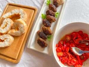 Cypriotische gehaktballetjes serveren met brood en paprika-tomaten salade